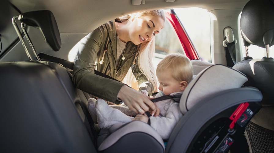 Jeunee femme installant un bébé dans son siège auto