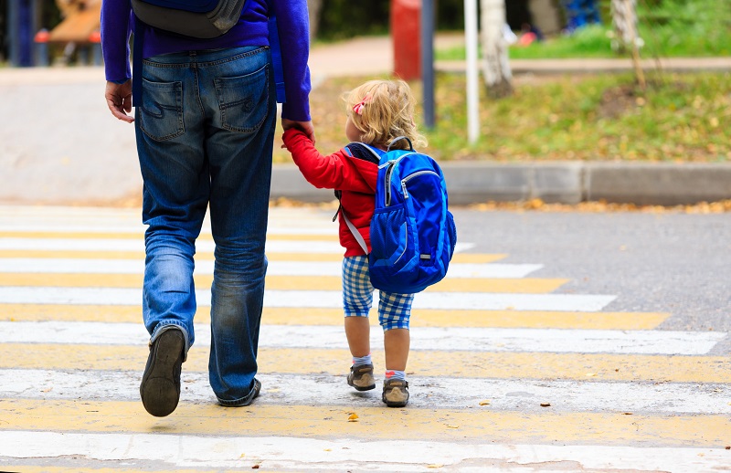Un père et sa fille, petite, sur le chemin de l'école